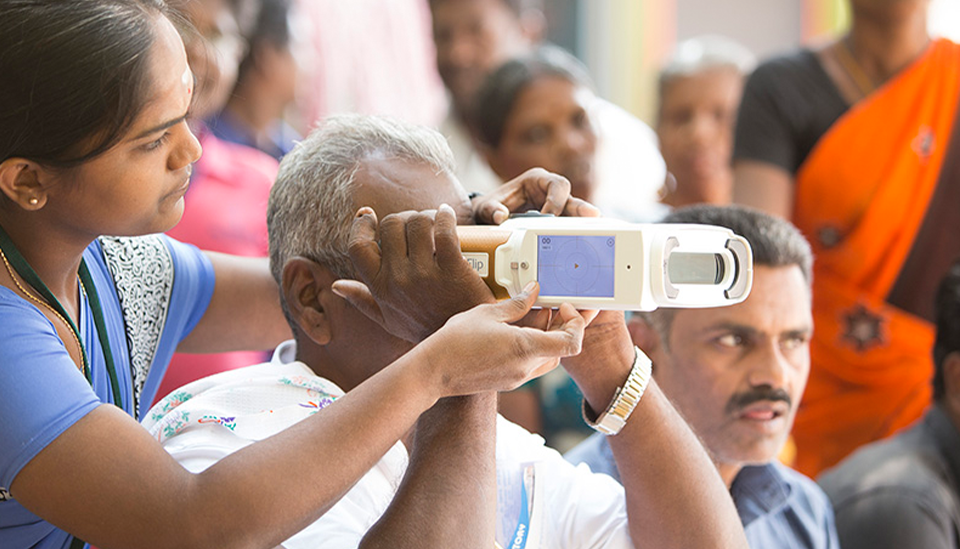woman measuring a patient's vision in India with the handheld QuickSee autorefractor