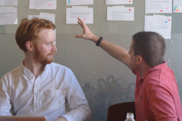 Fellows discussing ideas on a bulletin board